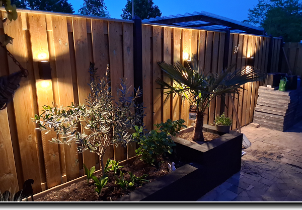 Nieuwe betonschutting met up and down buitenlampen aan de grenen tuinschermen.