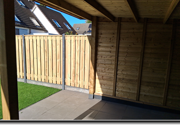 Nieuwe betonschutting in de kleur antraciet met grenen tuinschermen