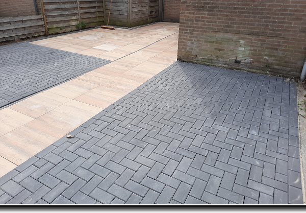 Parkeervakken van zwarte betonklinkers met een looppad van terra cotta terrasttegels