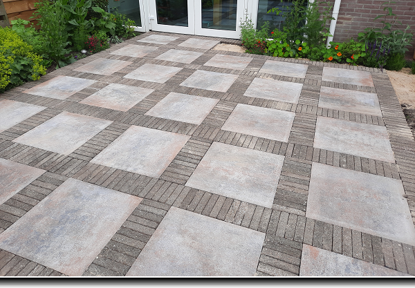 Straatwerk van grote tegels met daaromheen een rand van dikformaat stenen