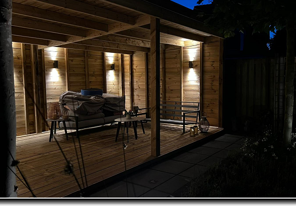 Overkapping met berging van grenen met zwarte potdeksel planken en witte up and down verlichting